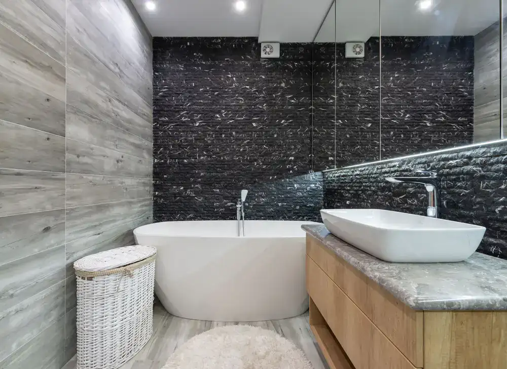 A sleek, contemporary bathroom featuring dark slate tiles and a modern freestanding tub